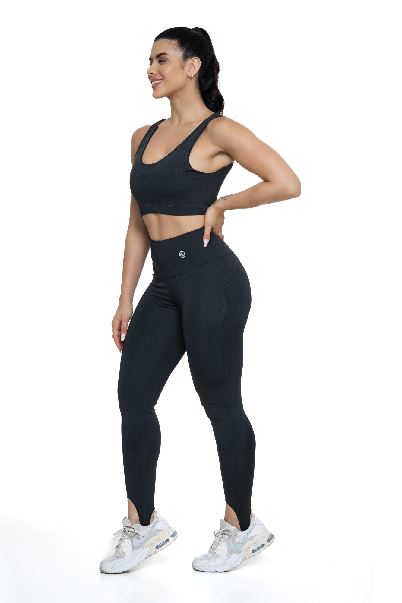 Conjunto fitness com legging preta de pezinho visto de lado, projetado para conforto e mobilidade, ideal para treinos com estilo e praticidade.