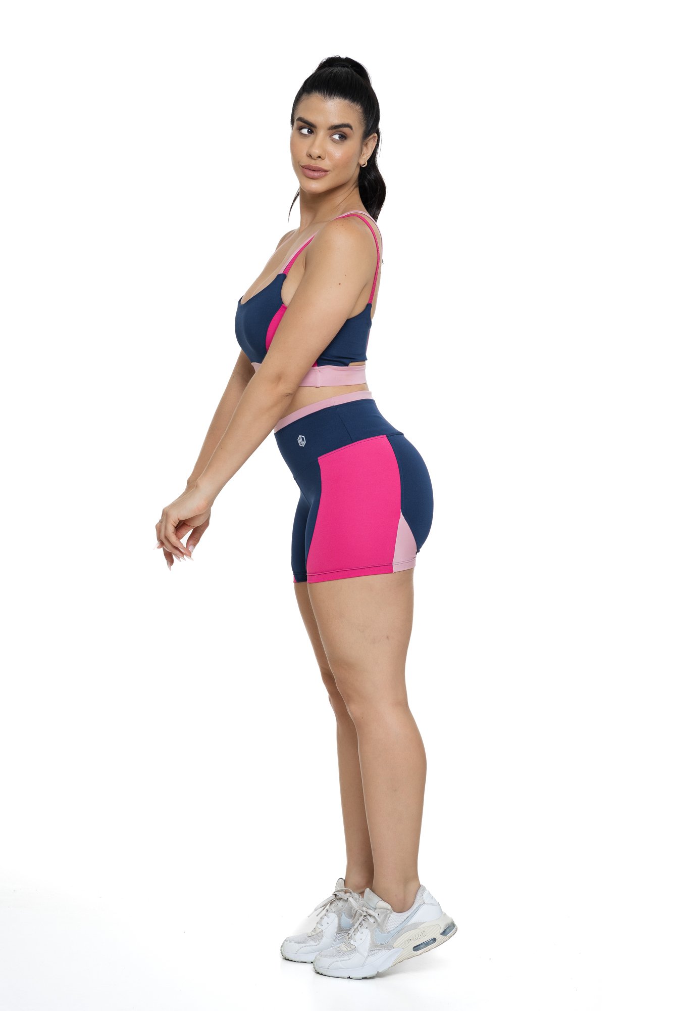 Conjunto bermuda fitness azul marinho e rosa com recortes visto de lado, ideal para treinos com estilo e praticidade.