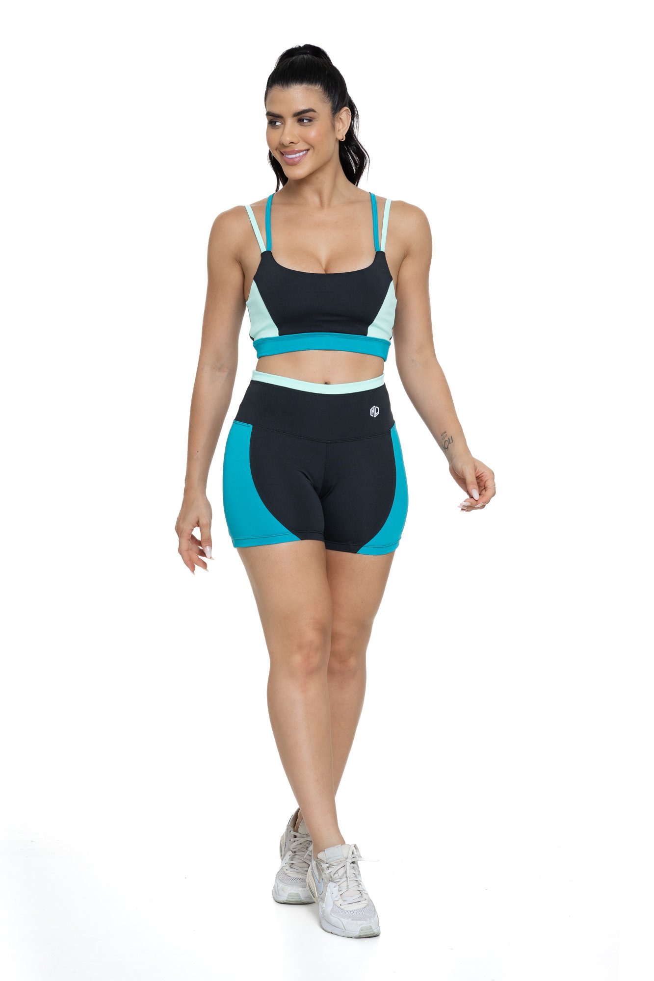 Conjunto bermuda fitness preto e verde com recortes visto de frente, ideal para treinos com estilo e praticidade.