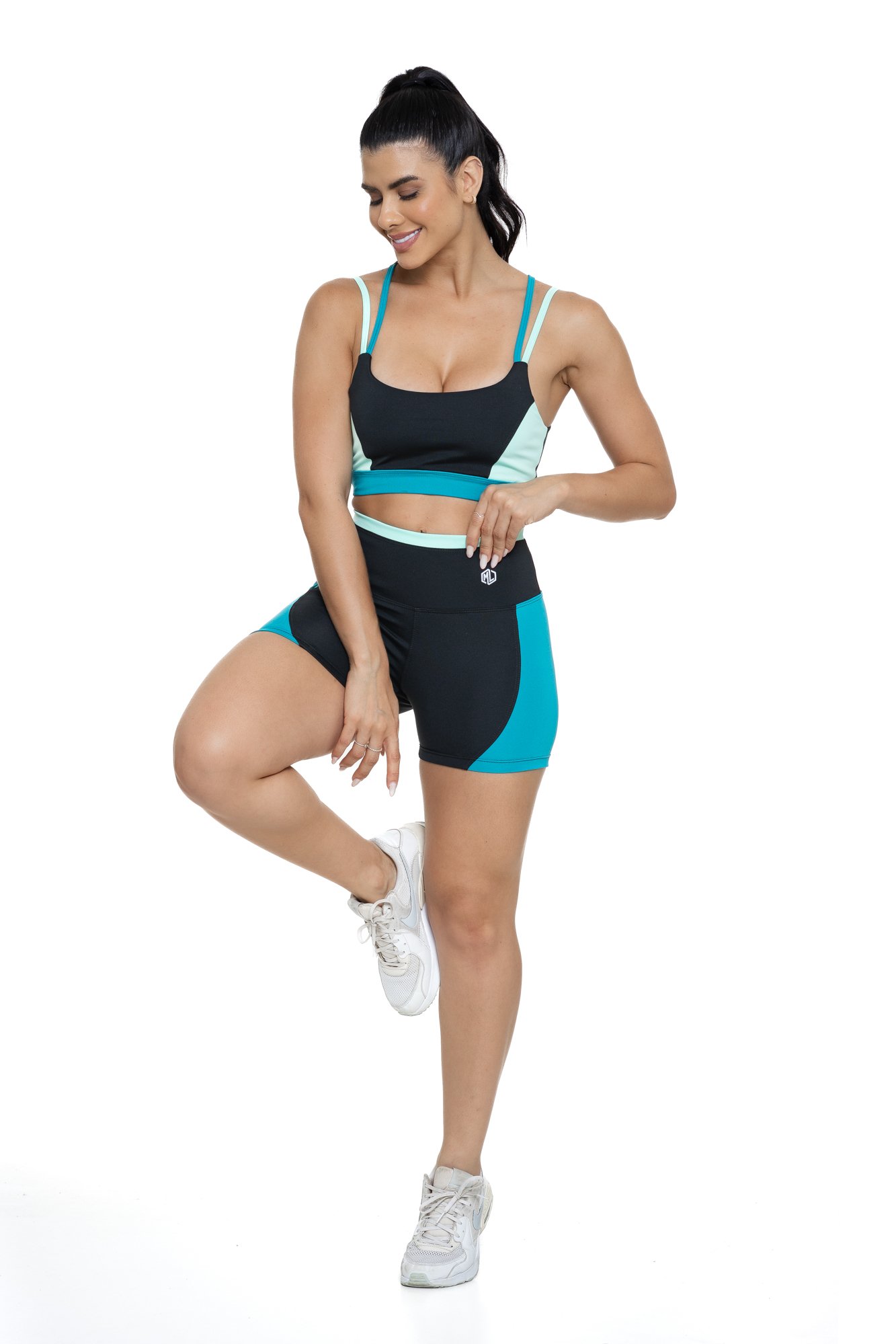 Conjunto bermuda fitness preto e verde com recortes visto de frente, ideal para treinos com estilo e praticidade.