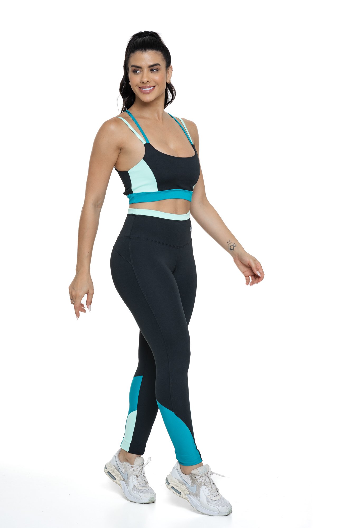 Conjunto fitness preto e verde com recortes visto de lado, projetado para conforto e mobilidade, ideal para treinos com estilo e praticidade.