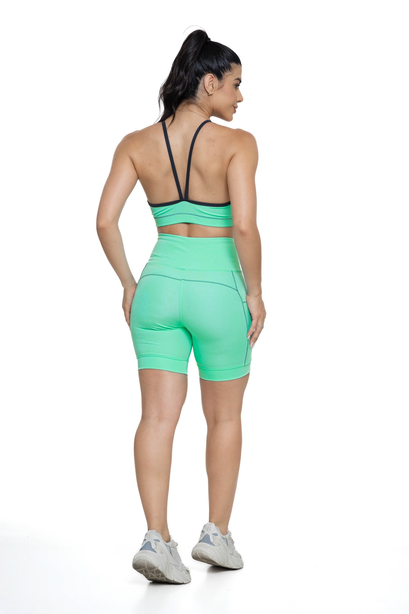 Conjunto bermuda feminino verde água e grafite com bolso visto de costas, ideal para treinos com estilo e praticidade.
