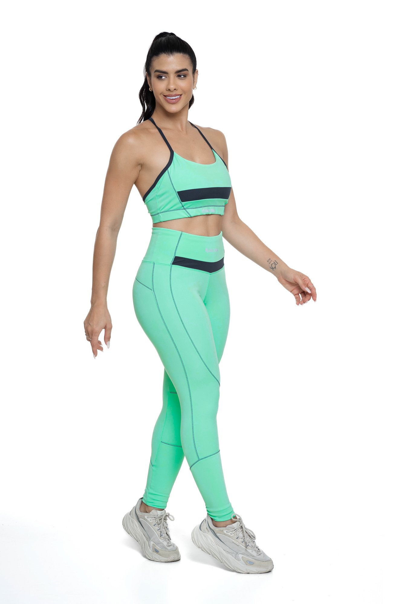 Conjunto feminino verde água e grafite com recortes visto de lado, projetado para conforto e mobilidade, ideal para treinos com estilo e praticidade